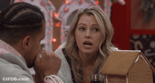 Man And Woman Sitting At Table With Gingerbread House GIF