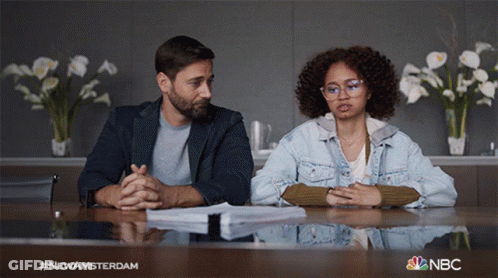 Man And Woman Sitting At Table With NBC Logo GIF