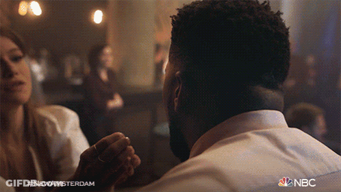 Man And Woman Sitting At Table With NBC GIF
