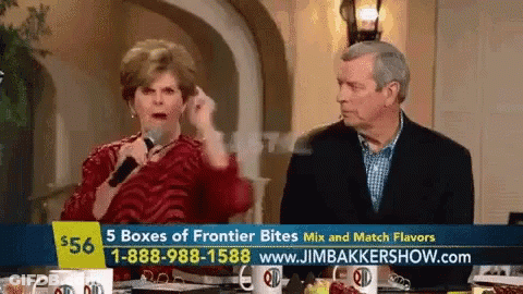 Man And Woman Sitting At Table With Sign Saying 5 Boxes Of Frontier Bites GIF