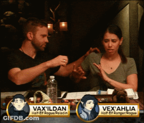 Man And Woman Sitting At Table With Vax Ildan Sign GIF