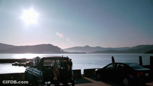 Man And Woman Sitting In Back Of Truck Near Lake GIF