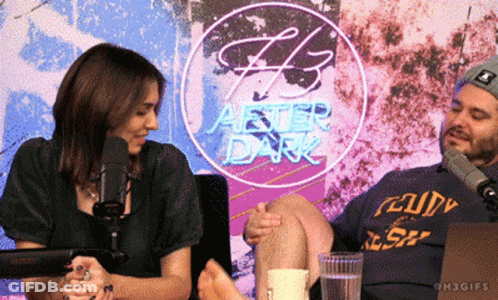 Man And Woman Sitting In Front Of After Dark Neon Sign GIF