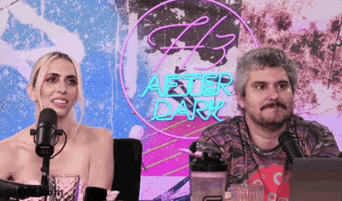 Man And Woman Sitting In Front Of After Dark Neon Sign GIF