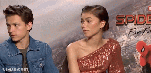 Man And Woman Sitting In Front Of Spider-Man Poster GIF