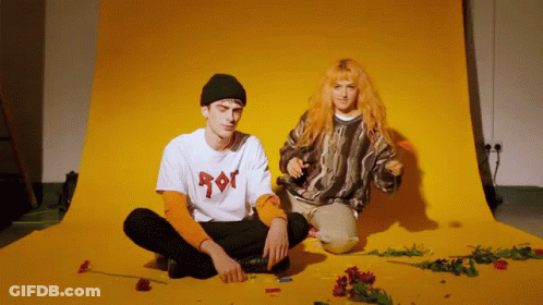 Man And Woman Sitting In Front Of Yellow Background GIF