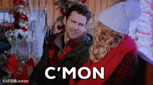 Man And Woman Sitting Next To Christmas Tree Smiling GIF