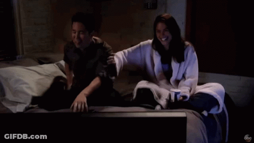 Man And Woman Sitting On Bed Watching TV With ABC Logo GIF