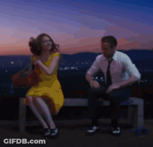 Man And Woman Sitting On Bench With City Background GIF