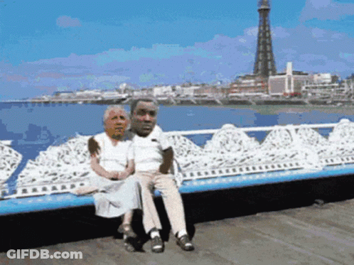 Man And Woman Sitting On Bench With Tower GIF