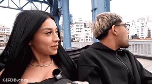 Man And Woman Sitting On Bridge With EP Necklace GIF