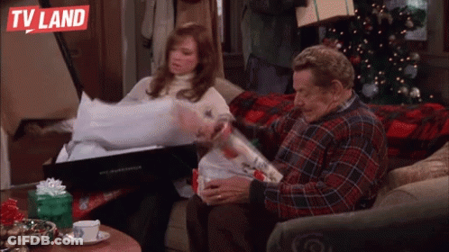 Man And Woman Sitting On Couch In Front Of Christmas Tree And TV Land Logo GIF