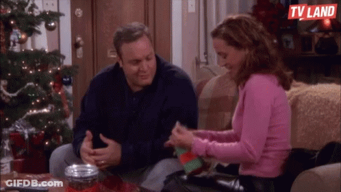 Man And Woman Sitting On Couch Near Christmas Tree GIF