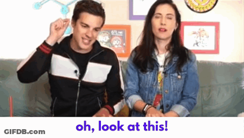 Man And Woman Sitting On Couch Saying Oh Look At This GIF