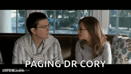 Man And Woman Sitting On Couch Saying Paging Dr Cory GIF