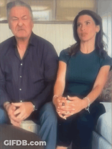 Man And Woman Sitting On Couch With Hands Folded GIF
