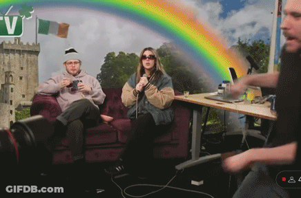 Man And Woman Sitting On Couch With Rainbow And Letter V GIF