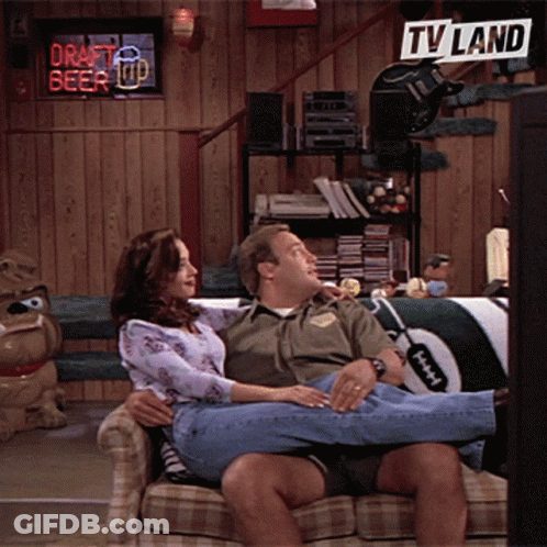 Man And Woman Sitting On Couch With TV Land Sign GIF