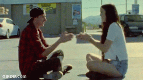 Man And Woman Sitting On Ground Holding Hands GIF