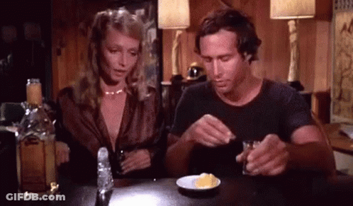 Man And Woman Sitting With Alcohol And Food GIF