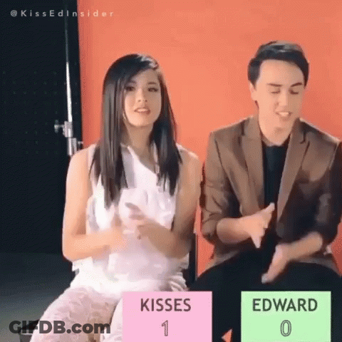 Man And Woman Sitting With Sign Kisses 1 Edward 0 GIF