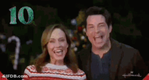 Man And Woman Smiling In Front Of Christmas Tree GIF