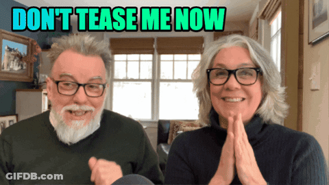 Man And Woman Smiling In Front Of Don't Tease Me Now Sign GIF