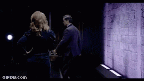Man And Woman Standing Before Purple Wall GIF