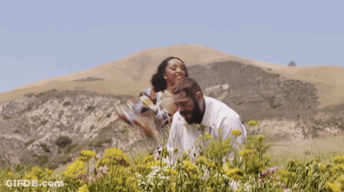 Man And Woman Standing In Field Of Flowers GIF