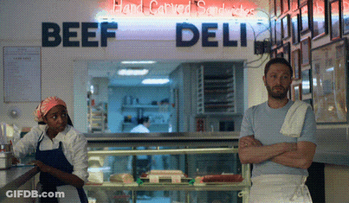 Man And Woman Standing In Front Of Beef Deli GIF