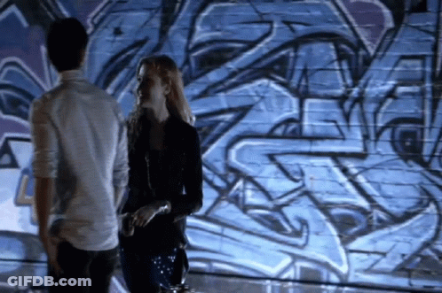 Man And Woman Standing In Front Of Graffiti Wall GIF