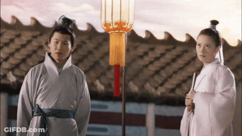 Man And Woman Standing In Front Of Roof With Lantern GIF