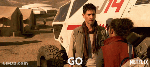 Man And Woman Standing In Front Of Vehicle Saying Go GIF