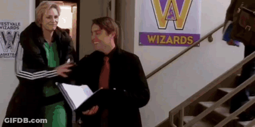 Man And Woman Standing In Front Of Wizards Sign GIF