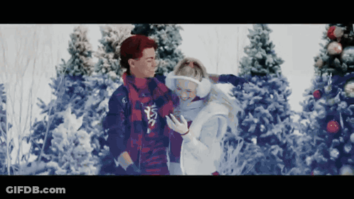 Man And Woman Standing In Snow Looking At Phone GIF