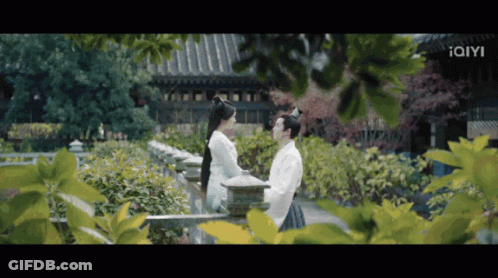 Man And Woman Standing Near Building With Iam GIF