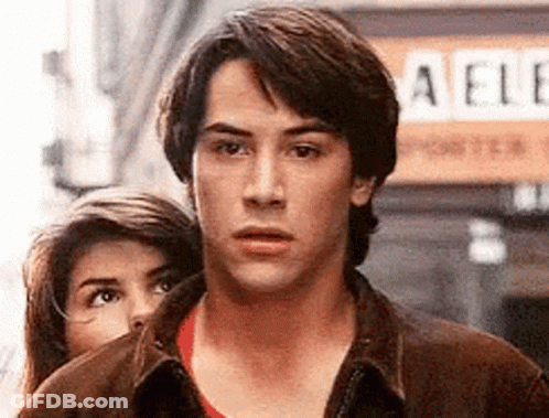 Man And Woman Standing Next To Each Other In Front Of Aelle Sign GIF