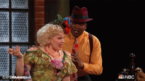 Man And Woman Standing Next To NBC Logo GIF