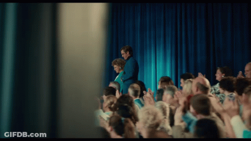 Man And Woman Standing On Stage In Front Of Crowd GIF