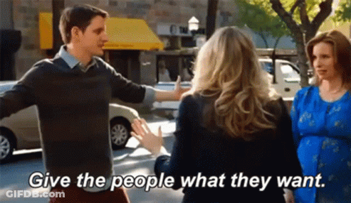 Man And Woman Talking On Street Saying Give The People What They Want GIF