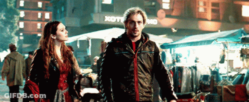 Man And Woman Walking Down Street In Front Of Store GIF