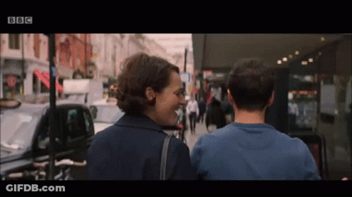 Man And Woman Walking Down Street With BBC Logo GIF