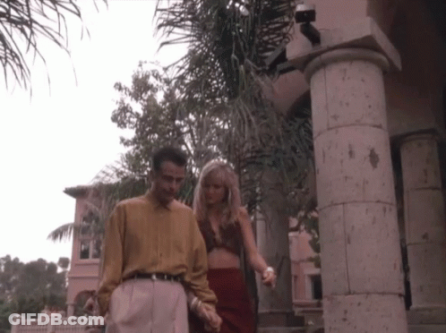 Man And Woman Walking Hand In Hand In Front Of Building GIF