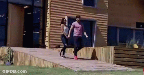 Man And Woman Walking In Front Of Building GIF