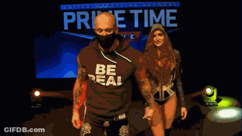 Man And Woman Walking In Front Of Home Time Live Sign GIF