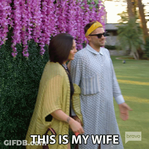 Man And Woman Walking In Front Of Purple Flowers Saying This Is My Wife Bravo GIF
