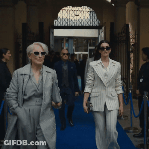 Man And Woman Walking On Blue Carpet In Front Of Building GIF