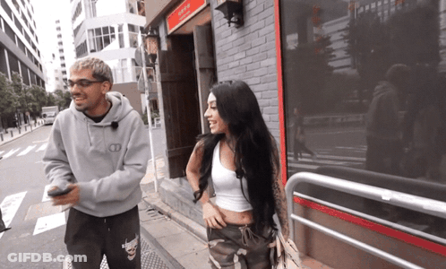 Man And Woman Walking Past Tokyo Building GIF