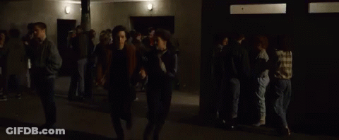 Man And Woman Walking Through Crowd In Dark Room GIF