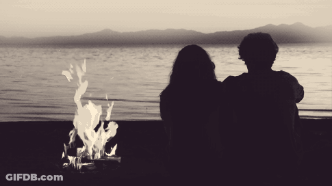 Man And Woman Watching Fire On Lake Shore GIF